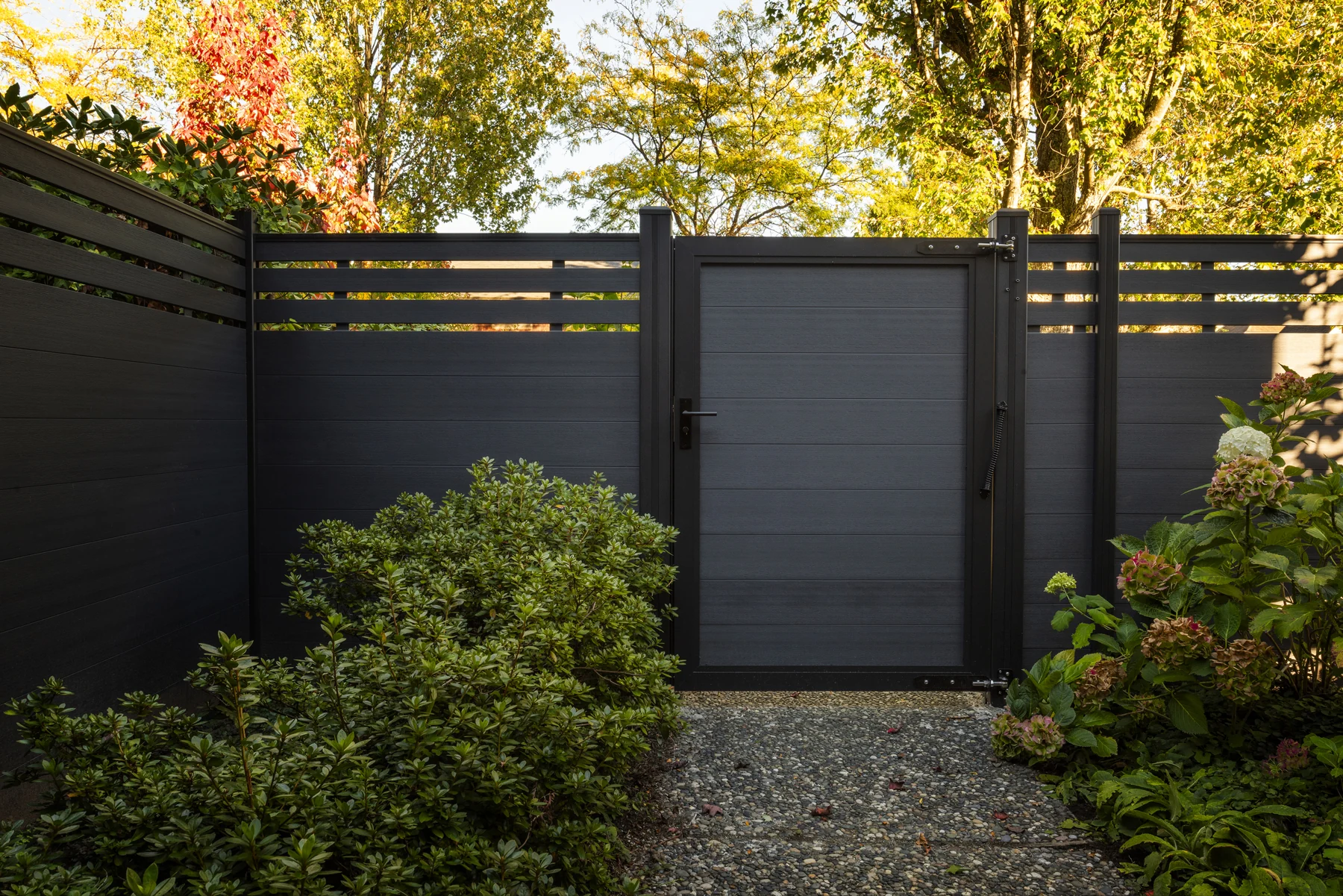 A single NeoLine composite garden gate beside matching partial trellis fencing